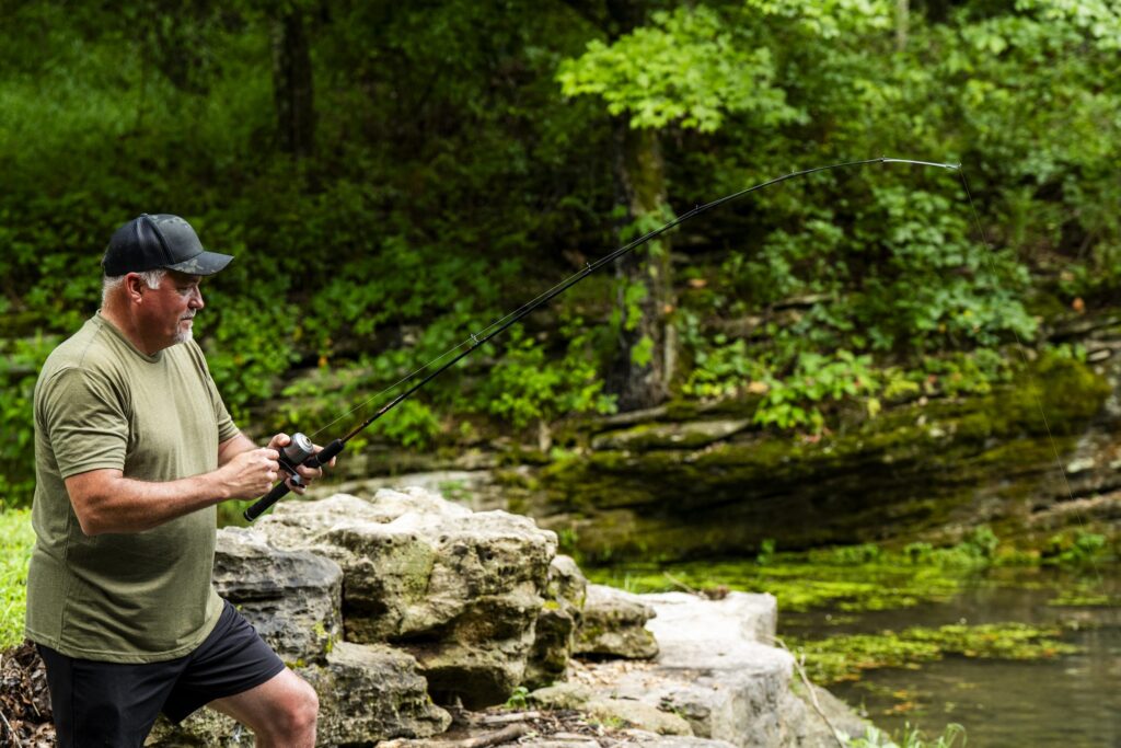 Angler fishing an Ugly Stik GX2 from a rocky creek bank in the Ozarks